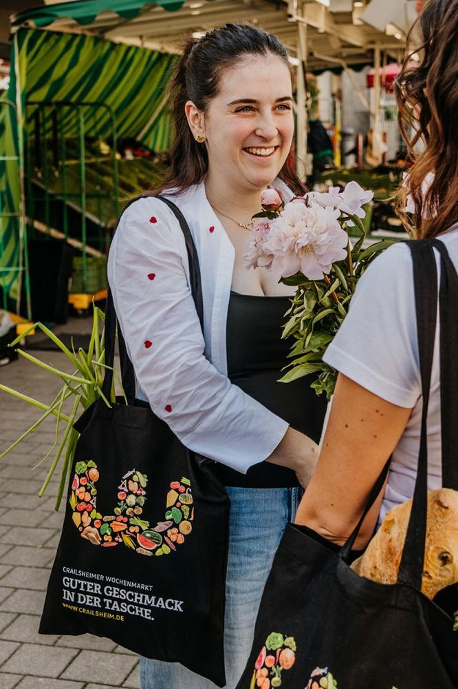 Stadtverwaltung eine Frau mit einer bunten Baumwolltasche auf einem Markt