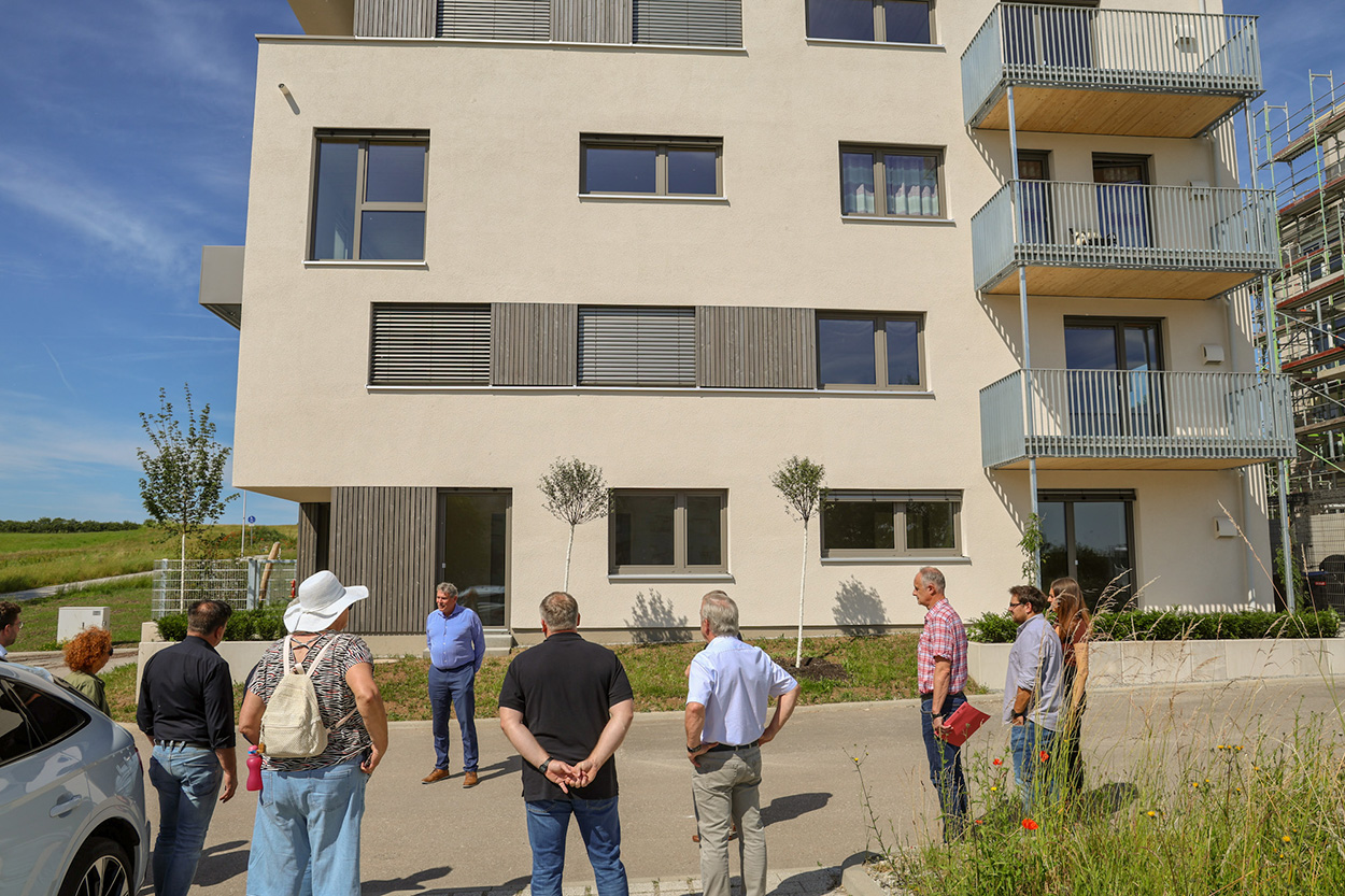 Stadtverwaltung Einige Menschen vor einem neuen Wohnhaus
