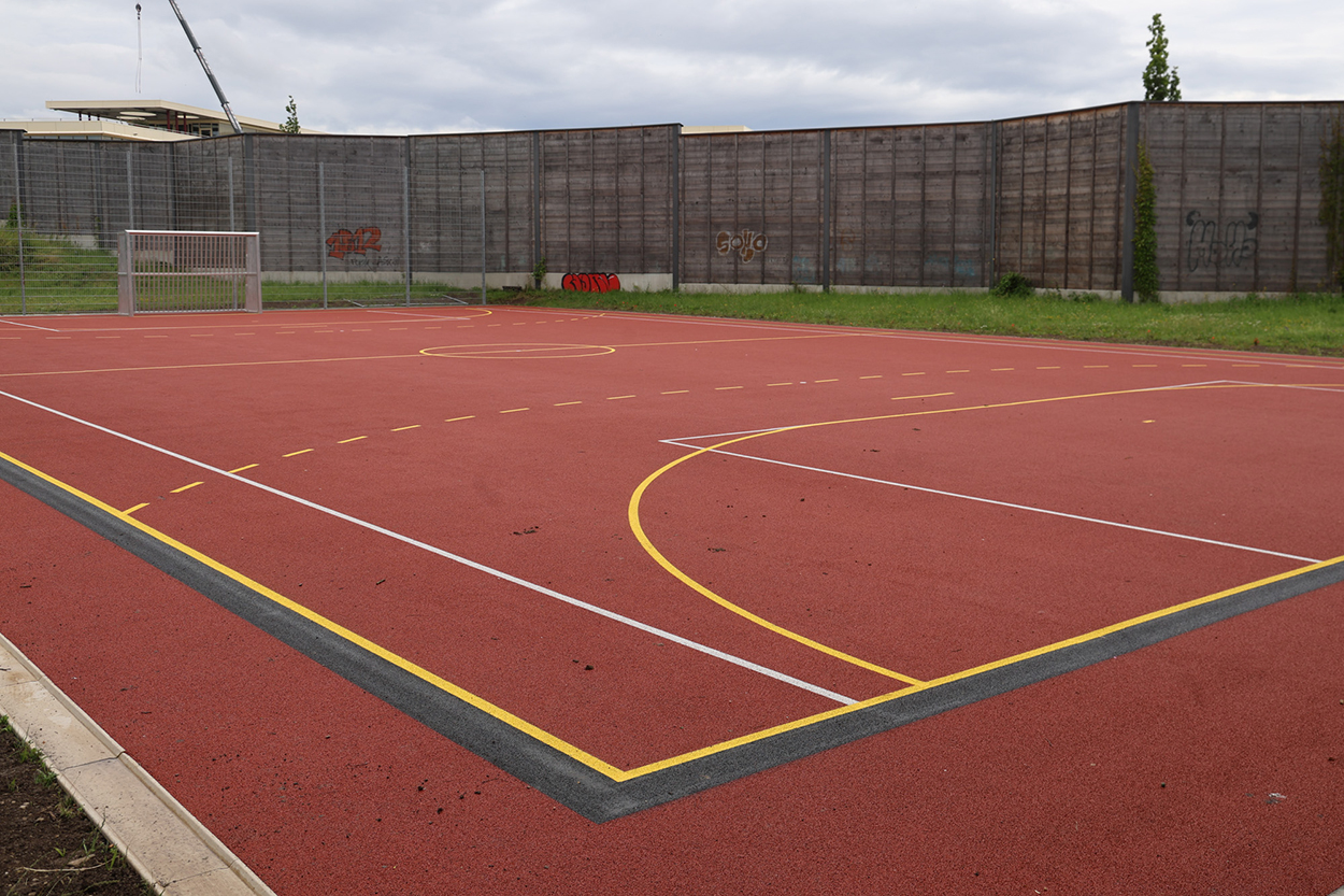 Stadtverwaltung Ein roter Hartplatz mit bunten Spielfeldlinien