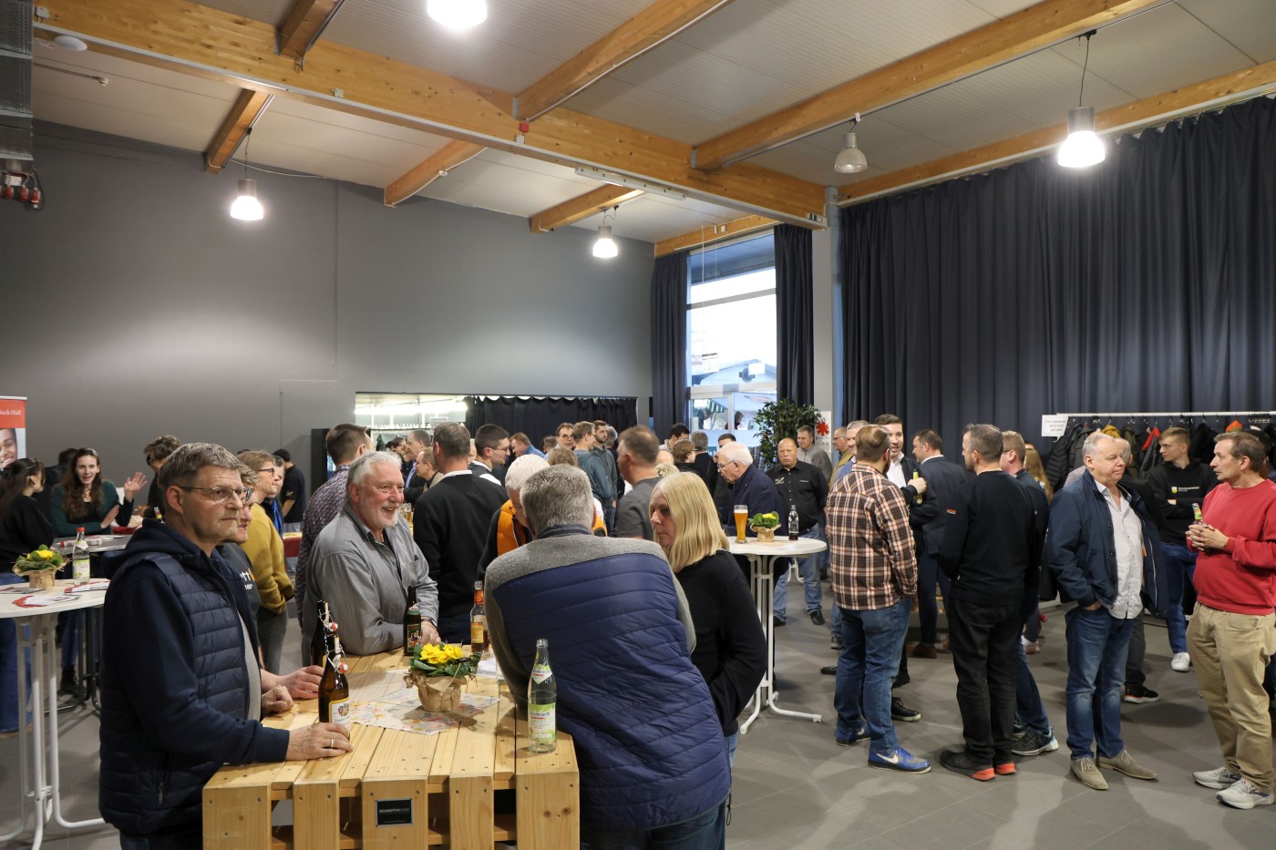 Viele Menschen an Stehtischen in einem Foyer mit viel Licht