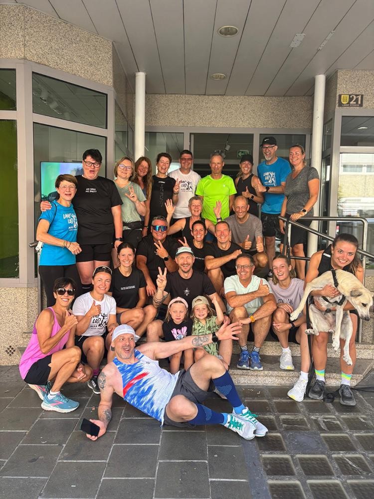 Trieger Eine sportlich angezogene Truppe albert vor einem Geschäftseingang für die Kamera