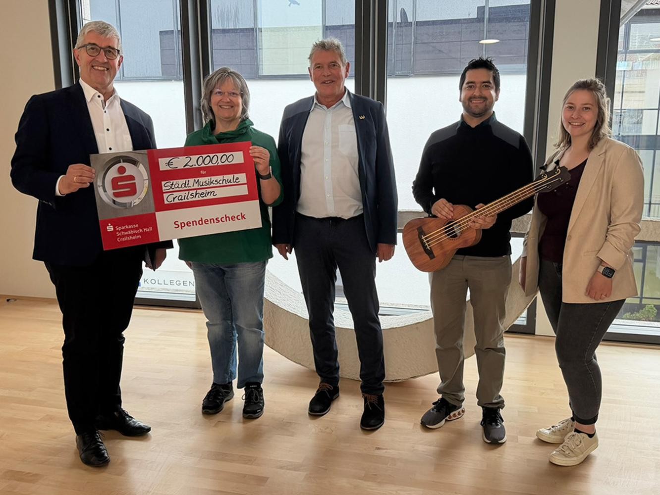 Stadtverwaltung Vier Personen stehen mit einem großen symbolischen Schck für ein Foto bereit