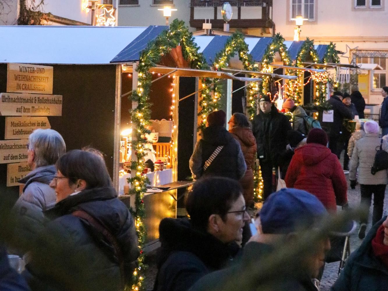 Stadtverwaltung viele Menschen auf einem erleuchteten Weihnachtsmarkt in der Dämmerung