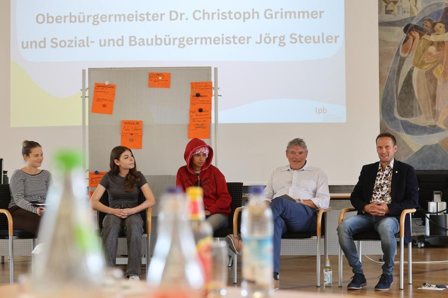 Fünf Personen vor eienr Leinwand sitzen auf Stühlen