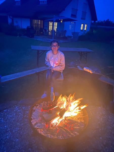 Mädchen am Feuer mit Stock und Stockbrot in der Hand