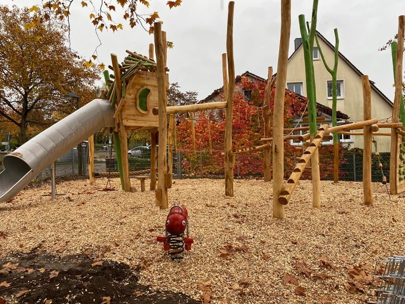 Ein Klettergerüst aus Holz auf einem Spielplatz mit Rutschröhre