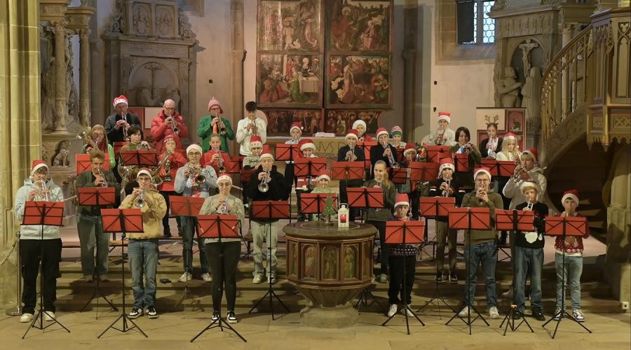 Eine Gruppe Bläster steht mit Nikolausmützen auf dem Kopf in einer Kirche und spielen