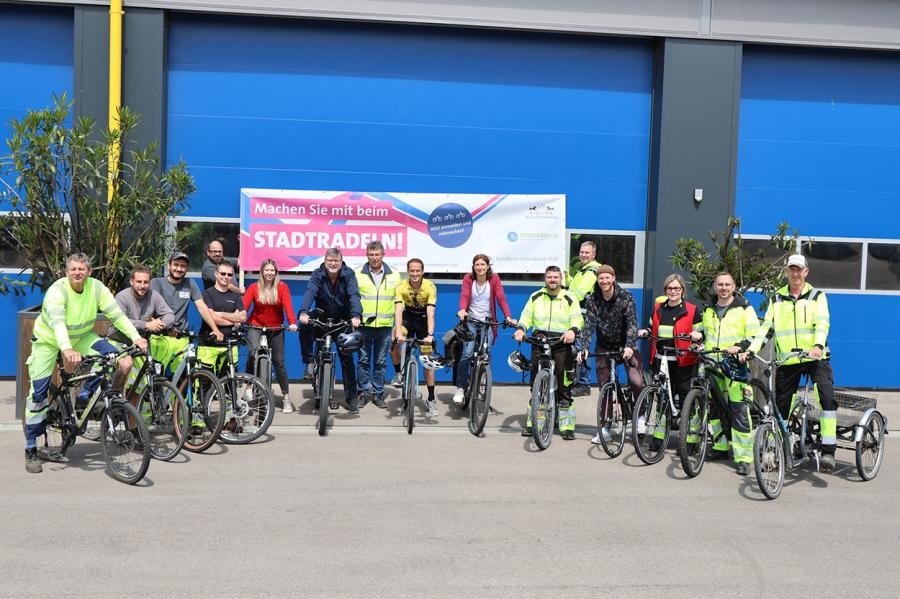 Eine Gruppe Fahrradfahrer steht mit Rädern vor einem Tor an dem ein Banner hängt