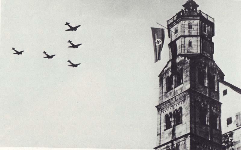 Turm mit Hakenkreuz-Flagge und 5 Düsenjäger die vorbeifliegen