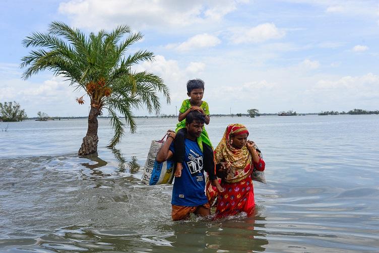 Familie in Bangladesch Shuvo Haven, die durchs Wasser laufen