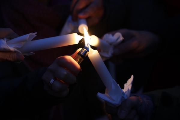 vier Kerzen werden mit einem Feuerzeug angezündet