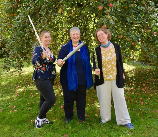 Drei Frauen an einem Obstbaum mit Instrumenten in der Hand
