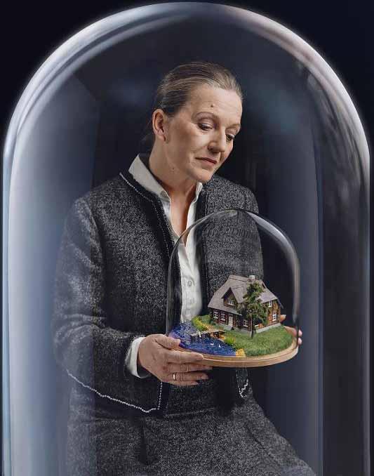 Bild von einer Frau die eine Glaskugel mit einem Haus darin in der Hand hält