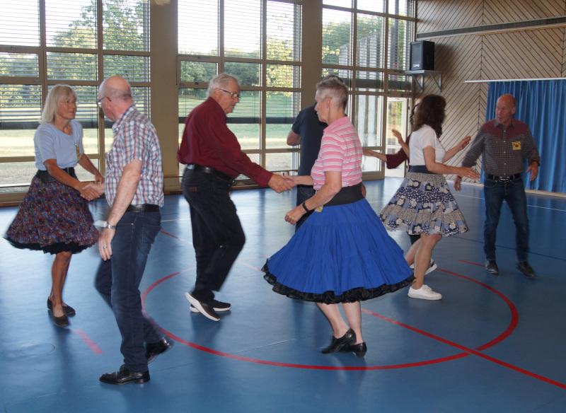 mehrer Paare, die in einer Turnhalle tanzen