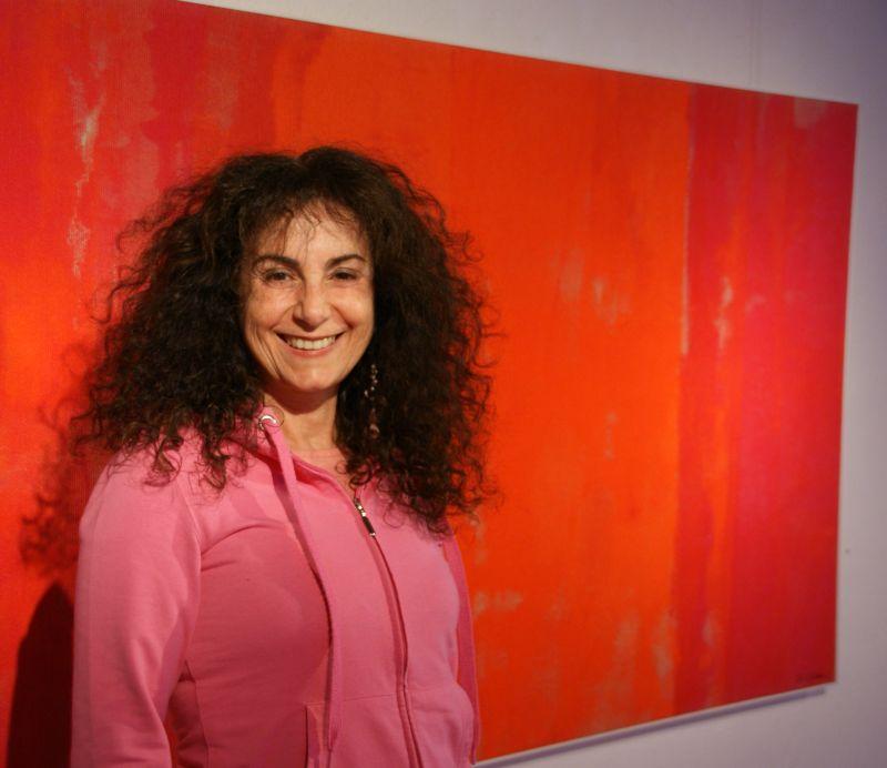 Portraitbild von einer Frau mit braunen lockigen Haaren vor einem roten Bild