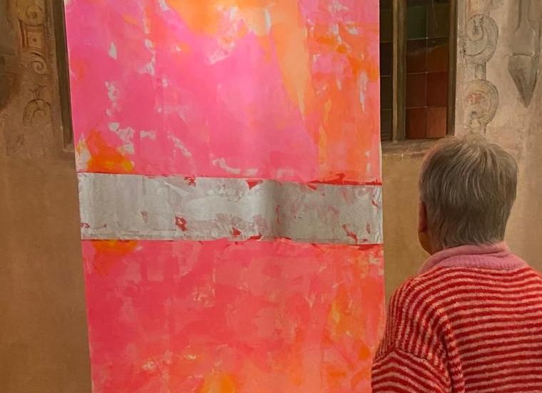 Textilobjekt mit pink und orangenen Farben und eine Frau schaut sich es an