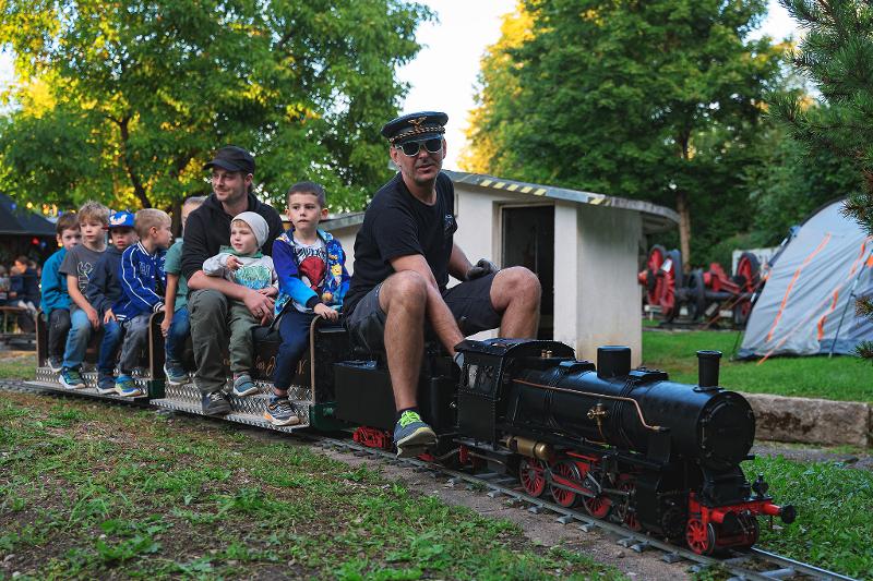 eine Dampfbahn mit Kinder und einem Schaffner fahren vorbei