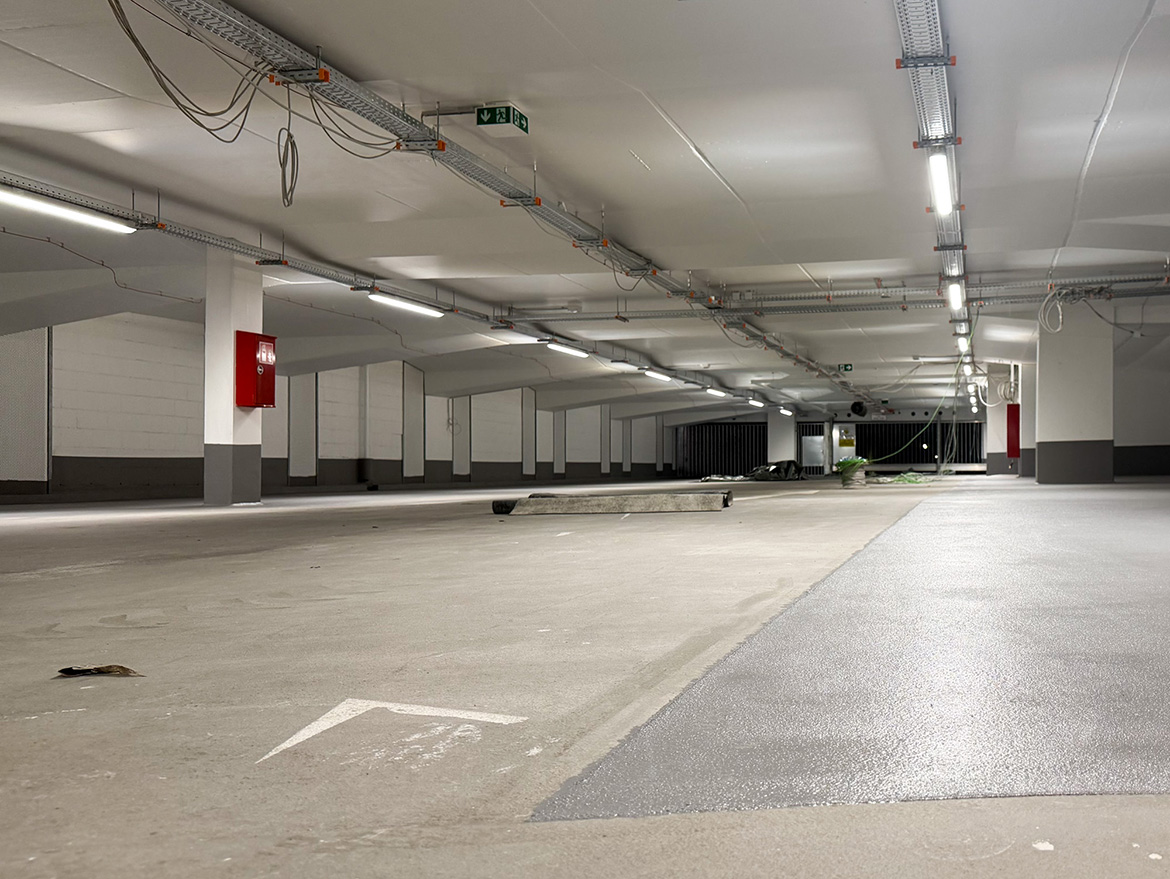 Eine erleuchtete Tiefgaragenebene mit unterschiedlichen Bodenbelägen