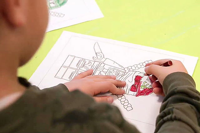 Junge malt auf einem Blatt Papier.