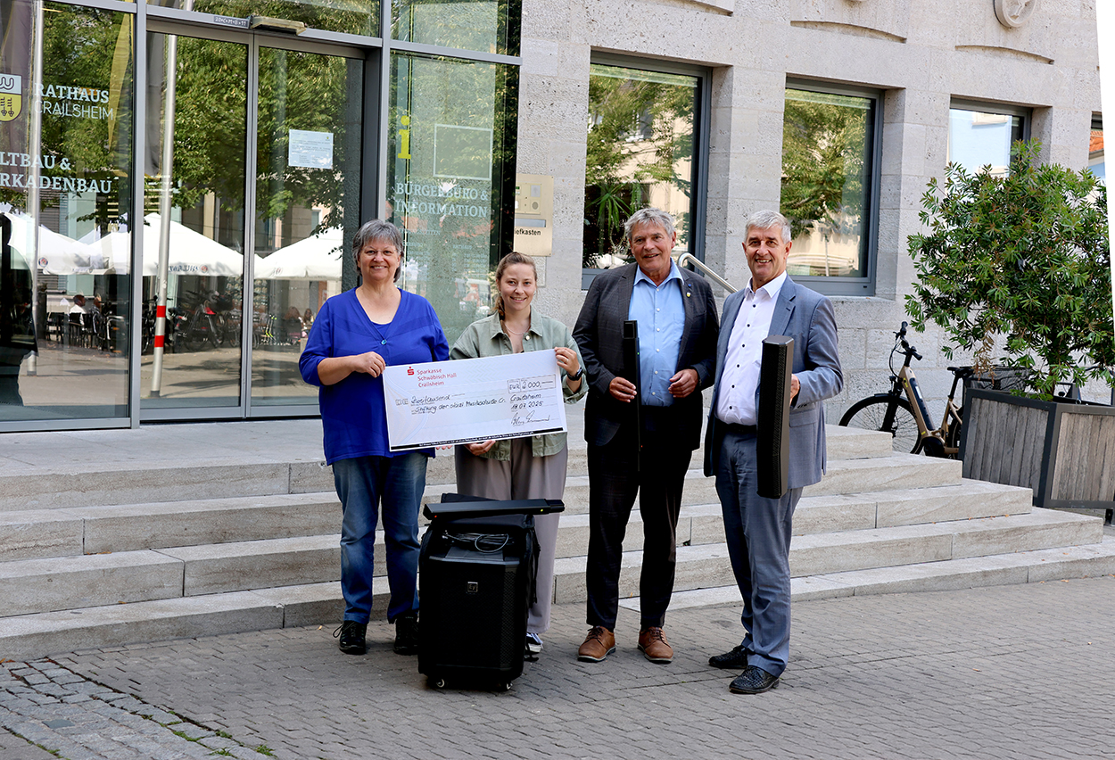Zwei Frauen halten einen Symbolschecke über einem Lautsprecher, zwei Männer daneben halten passende Utensilien.
