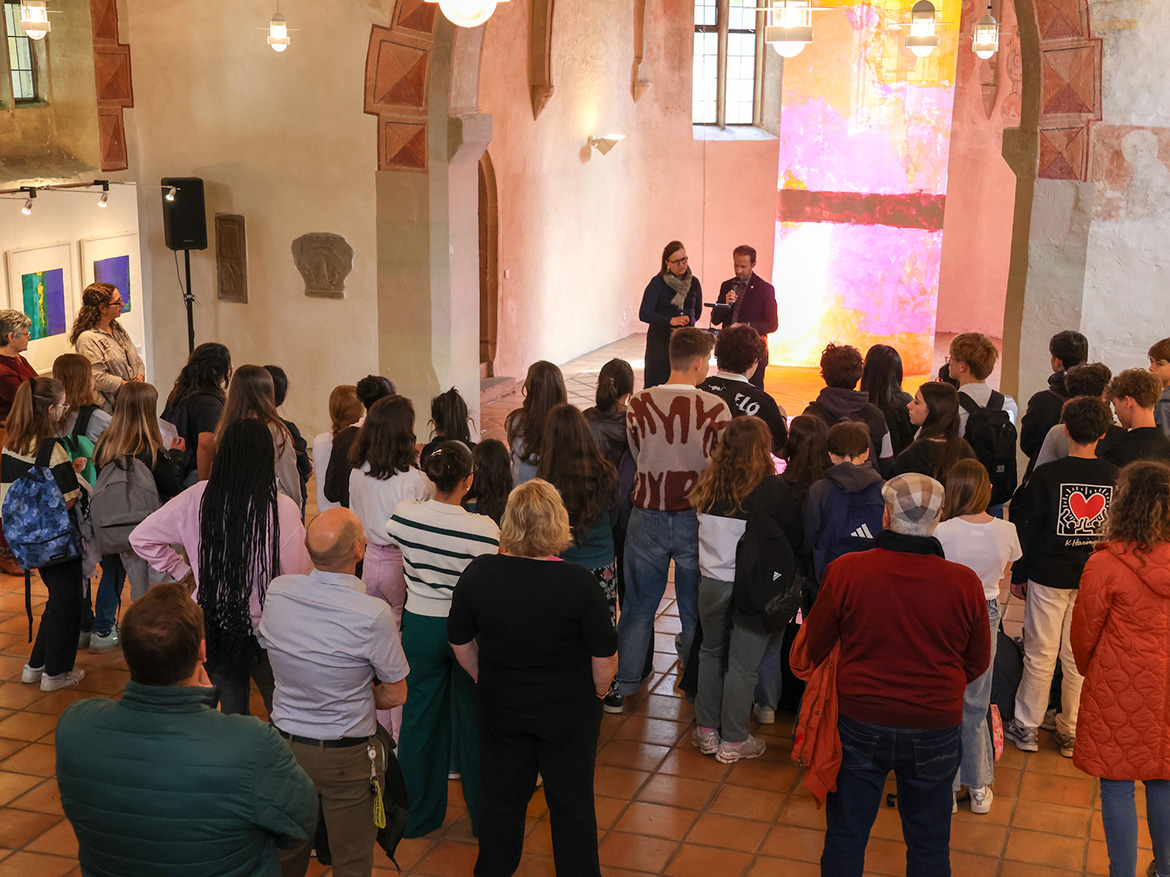 Eine Gruppe junger Menschen steht in einer Kapelle vor einem Rednerpult