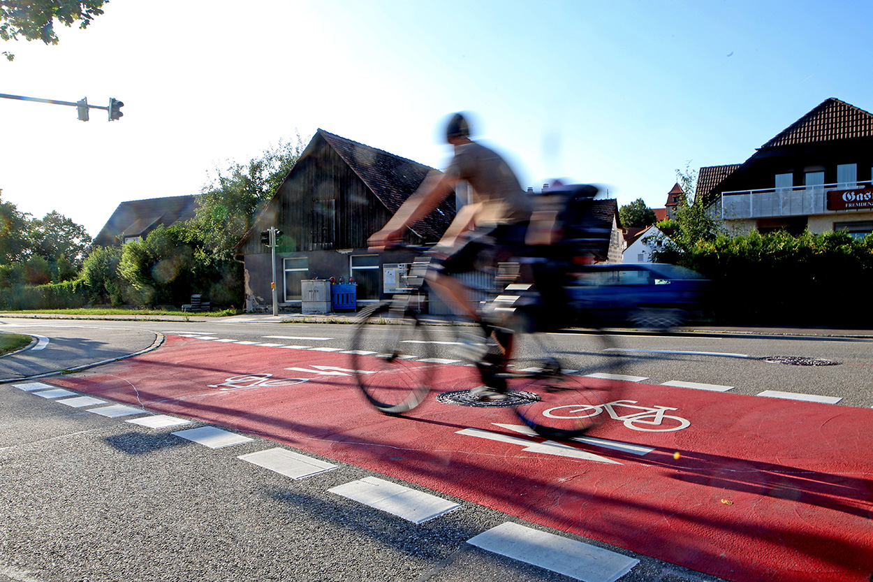 Ein Radfahrer ist auf einem roten Radweg unterwegs