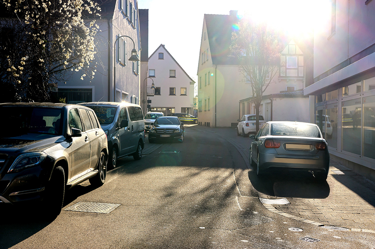 Eine Straße, in der mehrere Autos verkehrsgefährdend parken