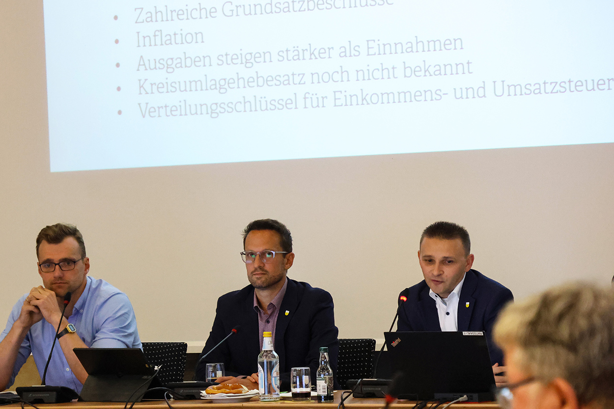 Drei Männer sitzen an einem Tisch, vor ihnen Laptops