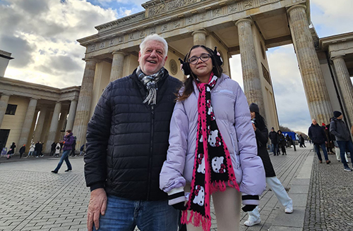 Ein älterer Herr und eine junge Frau stehen lächelnd vor dem Brandenburger Tor