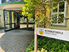 der Eingang zu einem Gebäude, davor ein Schild auf dem Musikschule steht