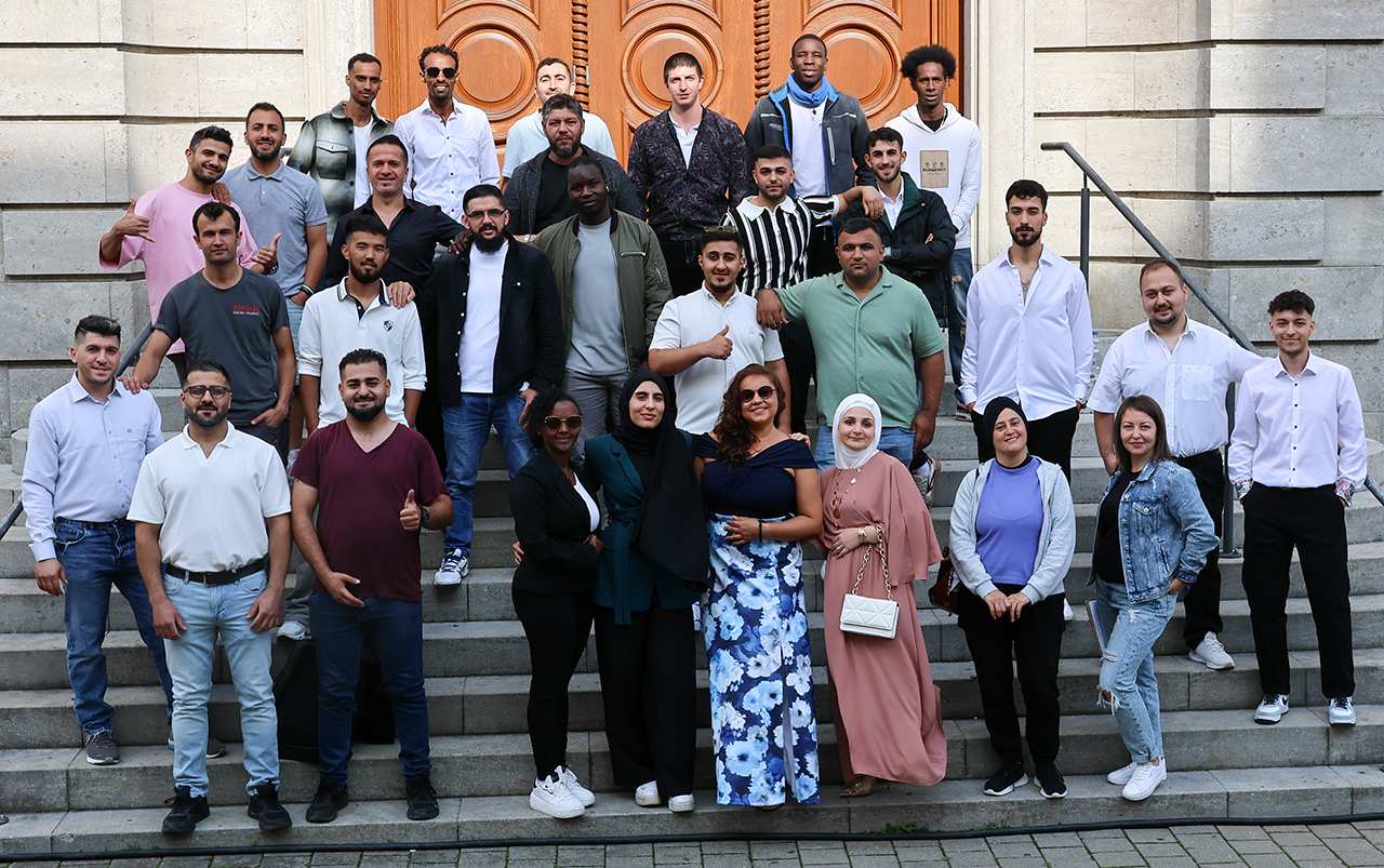 Einige Menschen stehen auf einer historischen Treppe und lachen in die Kamera