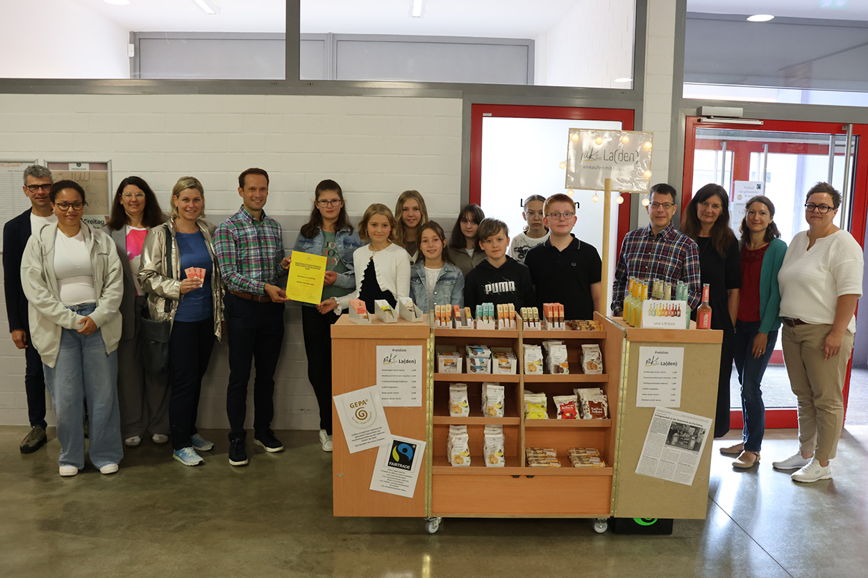 Eine Gruppe mit Erwachsenen und Jugendlichen steht für die Kamera hinter einem Ladentisch parat.
