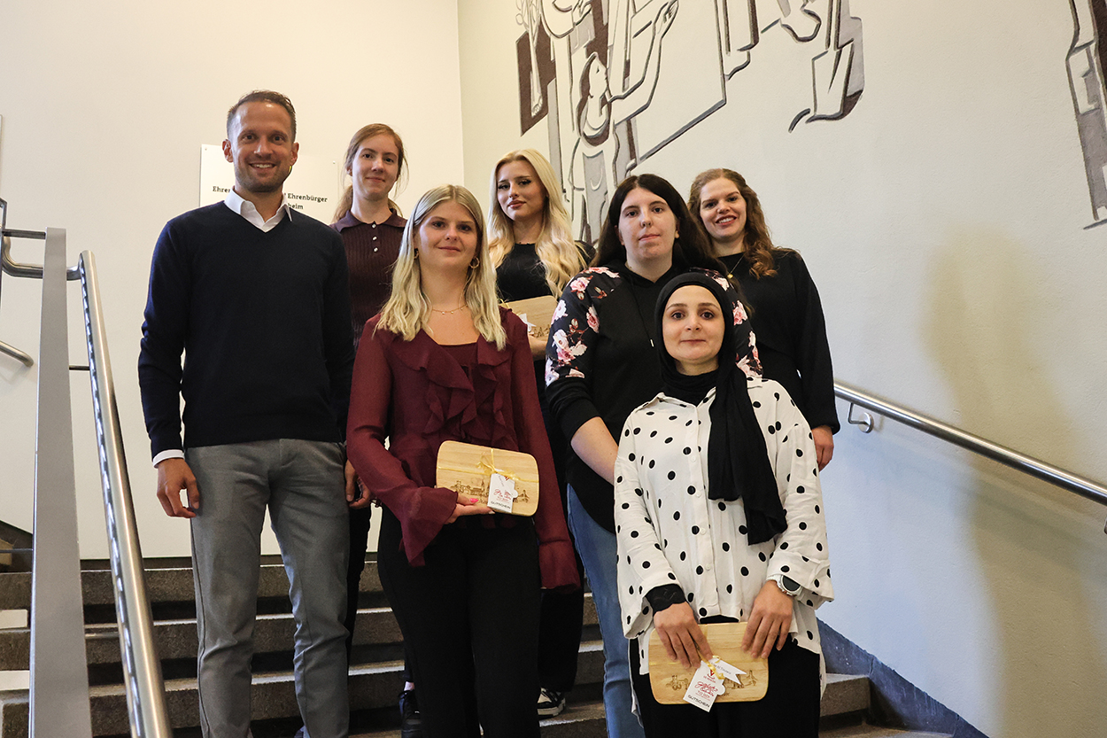 Ein mann und sechs Frauen posieren lächelnd auf einer Treppe für ein Foto