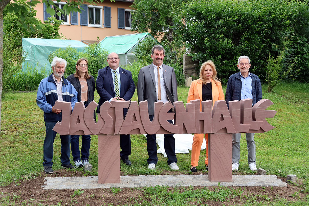 Stadtverwaltung einige Personen stehen hinter einem steinernen Schriftzug "Jagstauenhalle"
