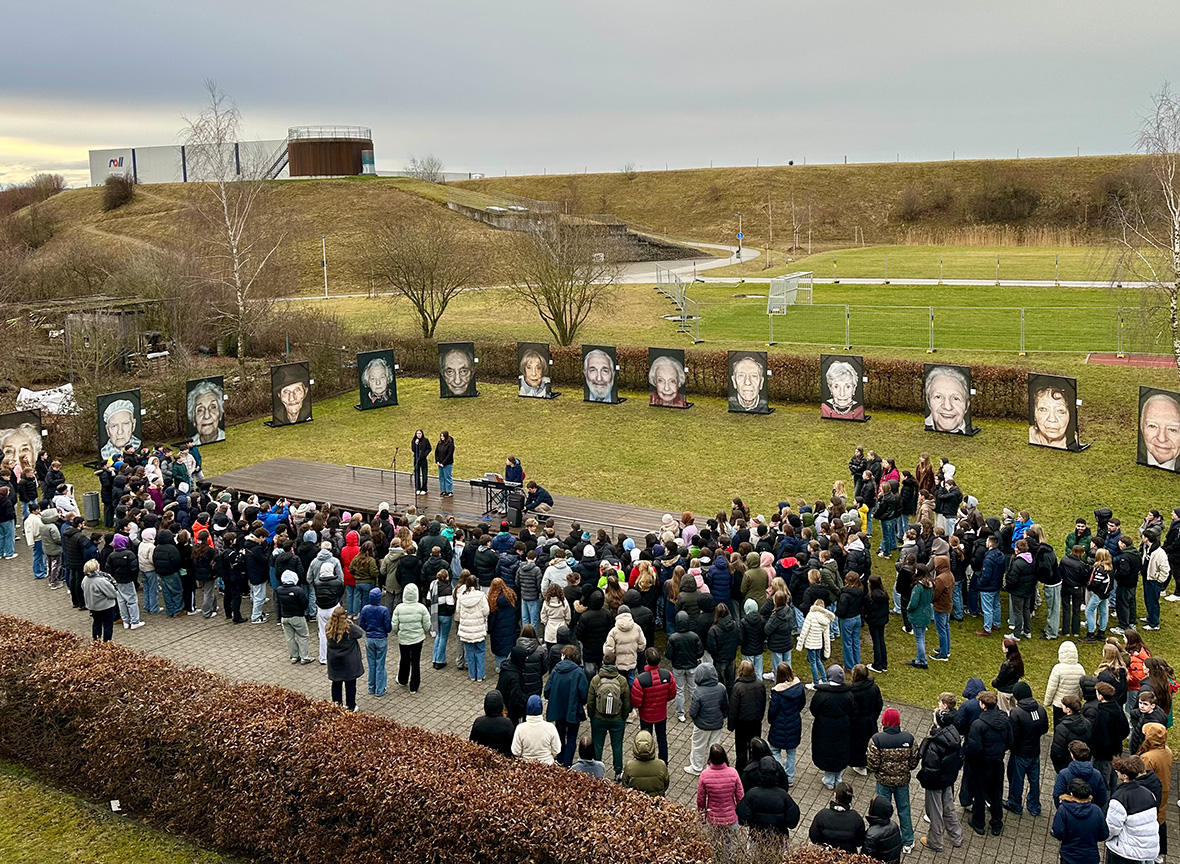 LMG Viele Menschen stehen auf eienr Wiese um große Porträtfotos herum