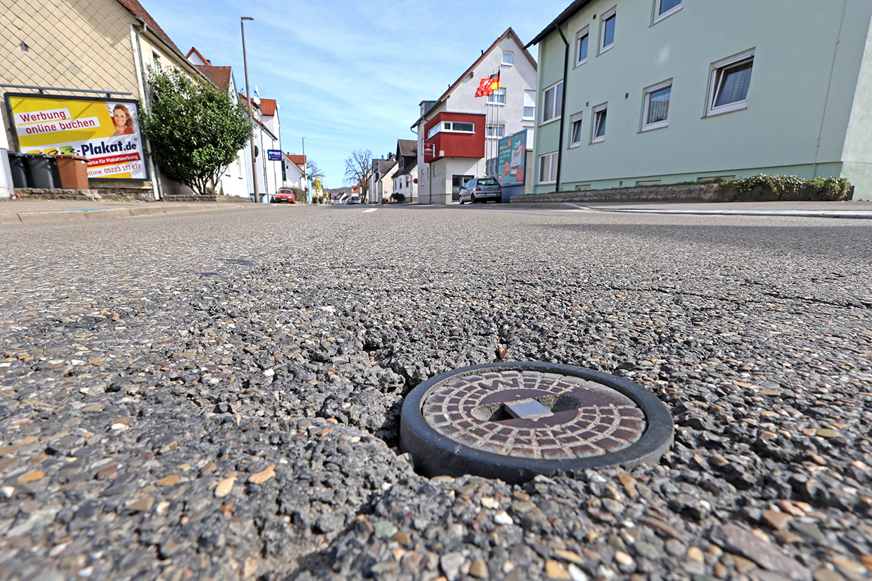 Stadtverwaltung Eine marode Stelle auf einer Straße, im Hintergrund Häuser