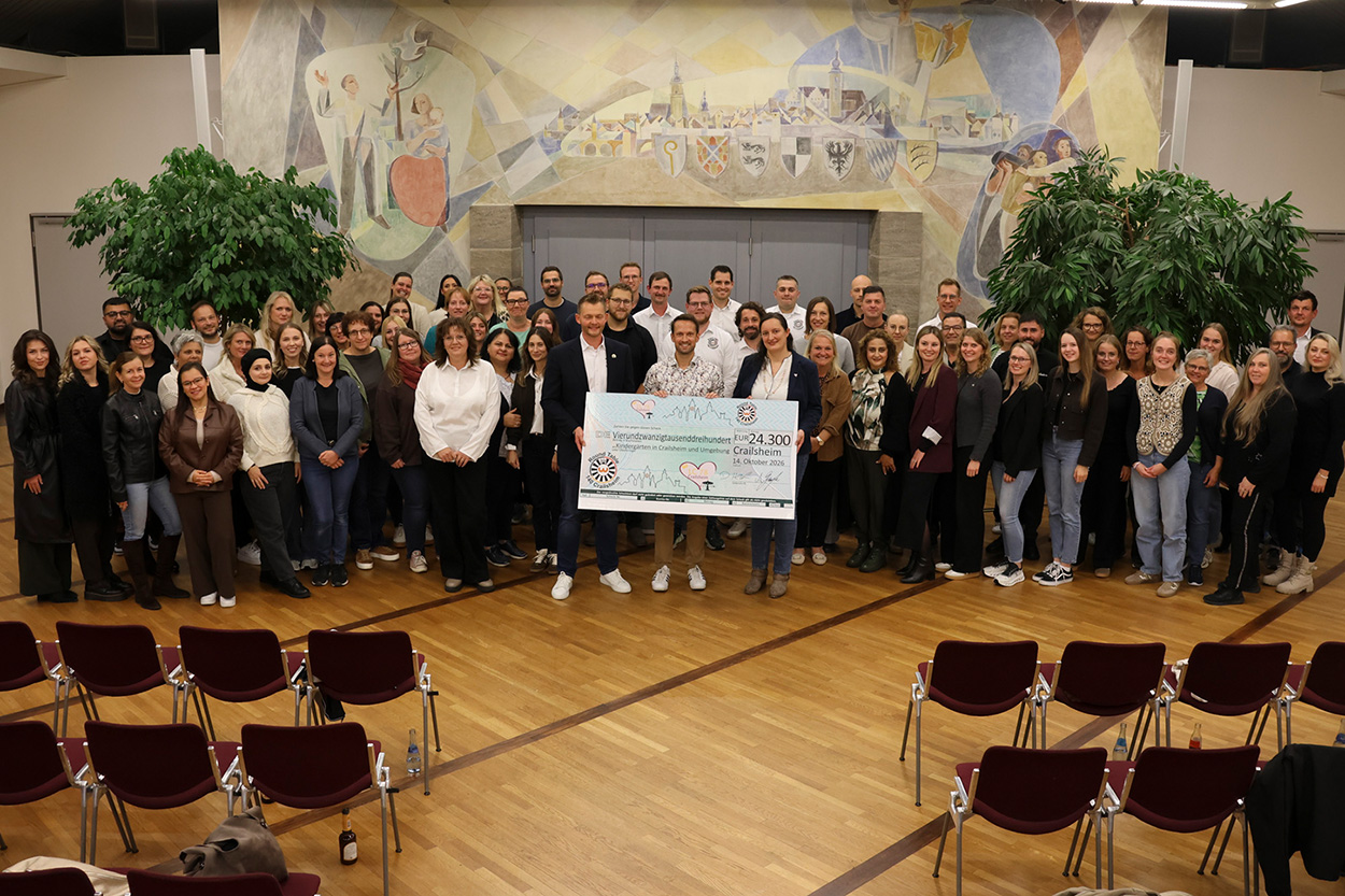 Viele Menschen stehen in einem Saal für ein Foto bereit, vorne ist ein übergroßer Scheck zu sehen