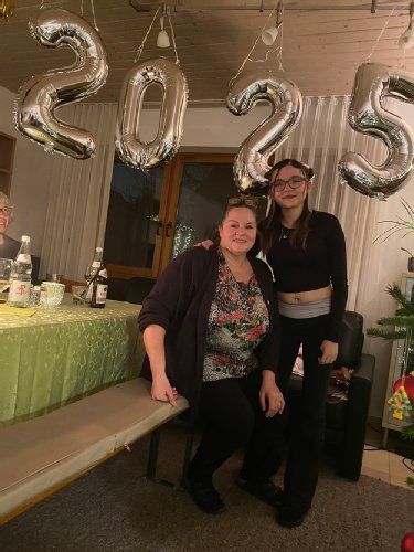 eine ältere Dame sitzt auf einer bank, eine junge Frau steht daneben, über ihnen schwebt die Zahl 2025