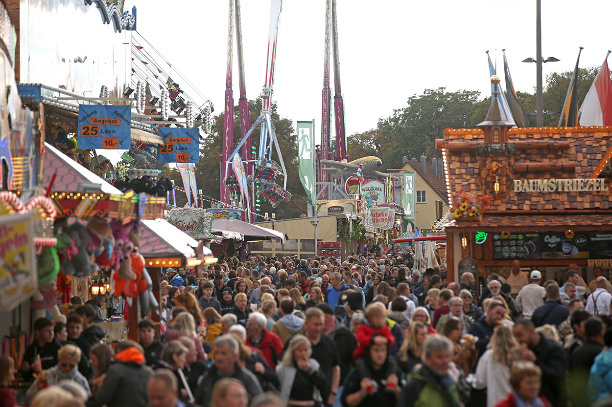 Ein segr gut besuchter Volksfestplatz mit Fahrgeschäften und Buden