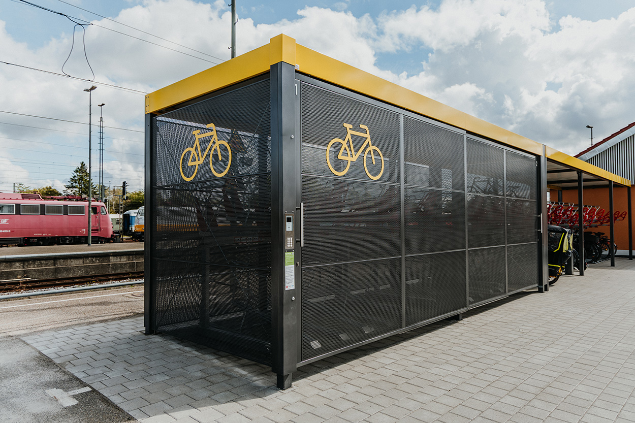 Ein schwarz-gelber Fahrradkäfig an einem Bahnhof