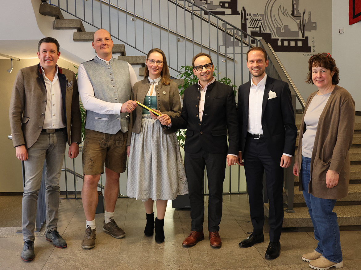 Mehrere Personen, teils in Tracht, stehen lächelnd für ein Foto bereit