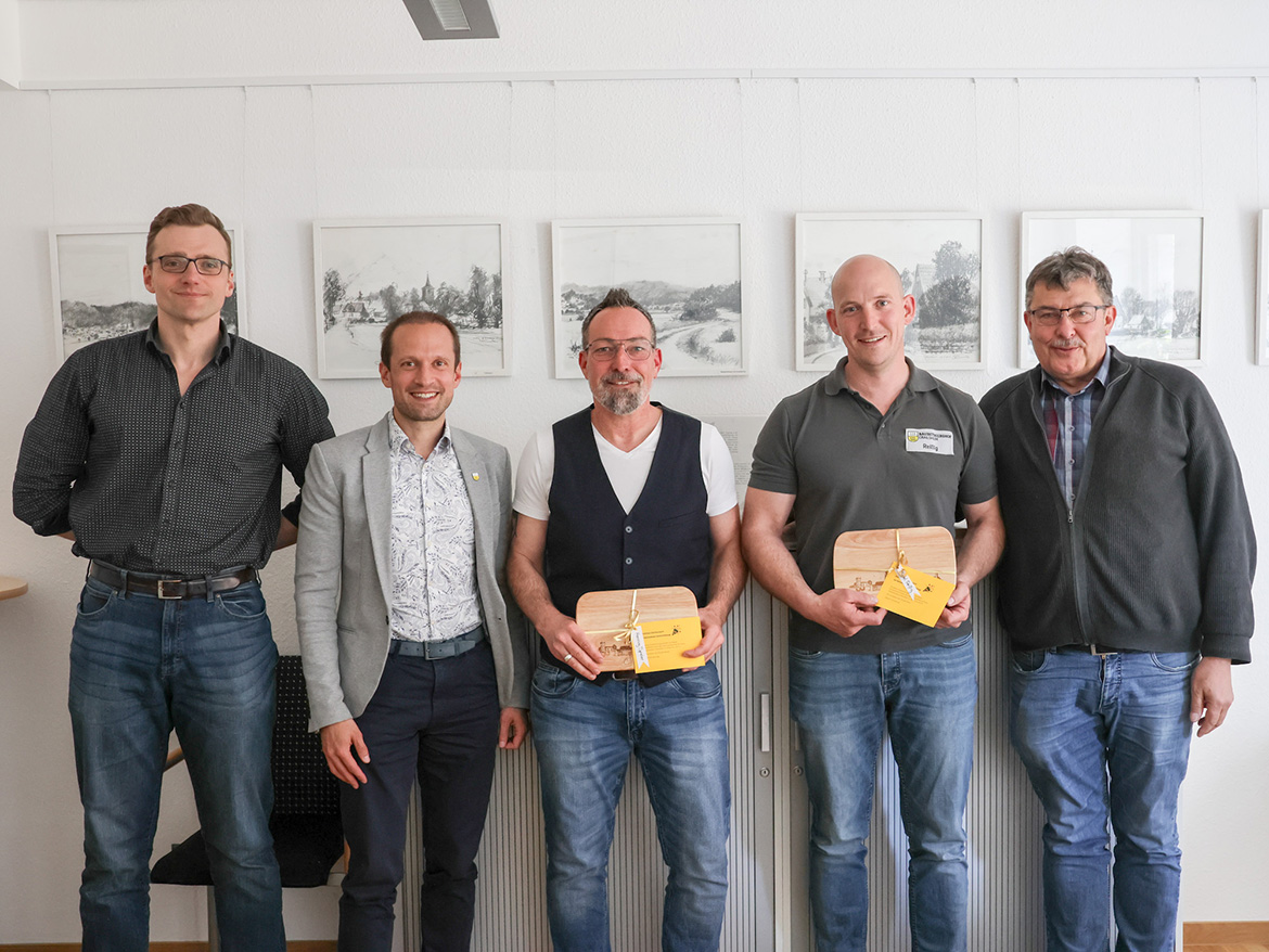 Fünf Männer stehen lächelnd für ein Foto bereit