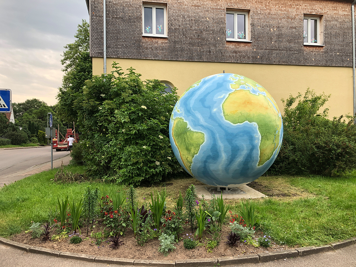 Stadtverwaltung Eine riesige Weltkugel steht in einem Garten vor einem großen Haus