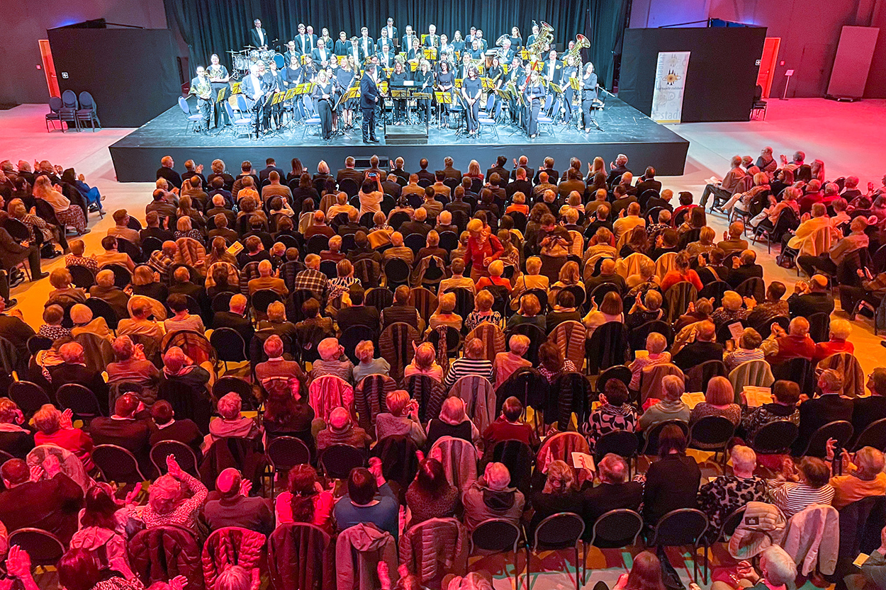 Ein großer Saal voller Menschen, auf der Bühne ein Orchester