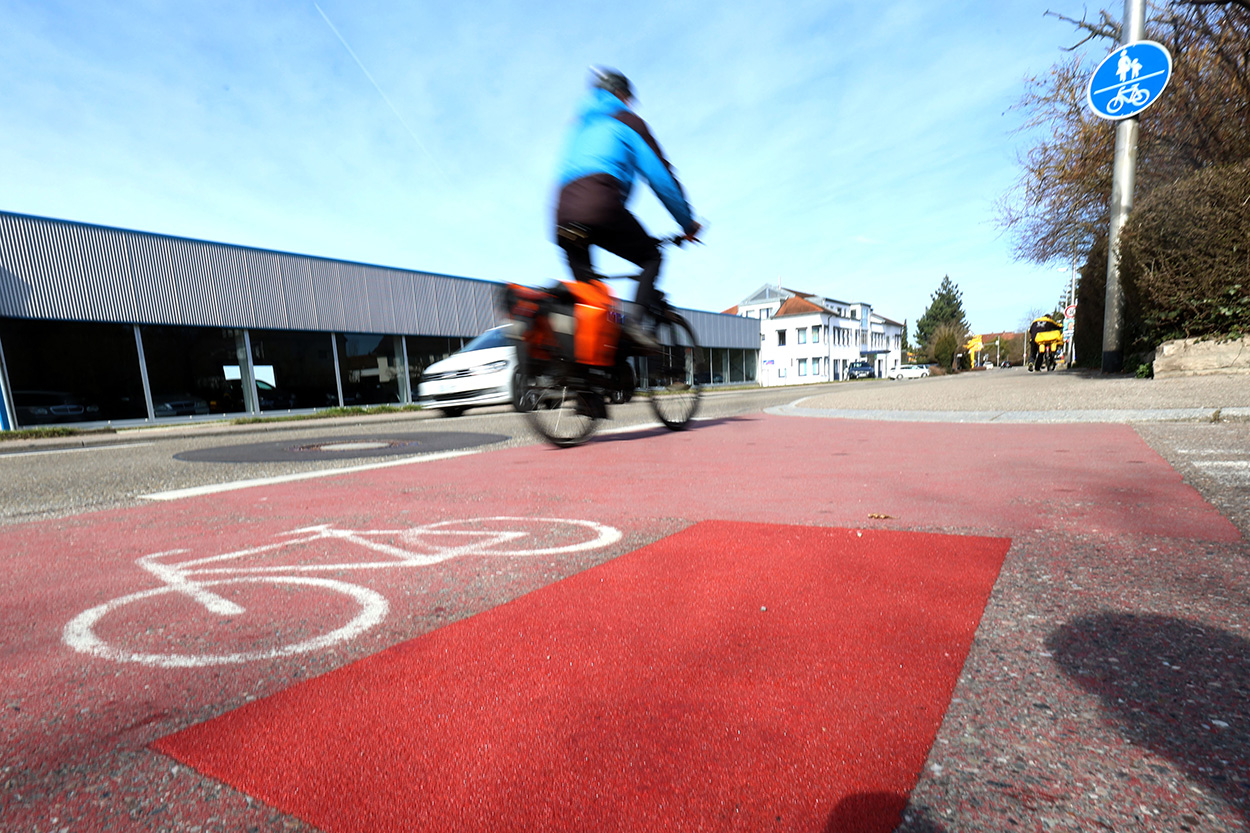 Ein Radfahrer fährt auf deer rechten Straßenseite auf einem Radweg.