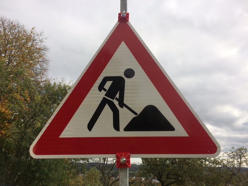 Stadtverwaltung (Symbolbild) Ein Bastellenschild, dreieckig mit rotem Rad und einem Bauarbeitersymbol