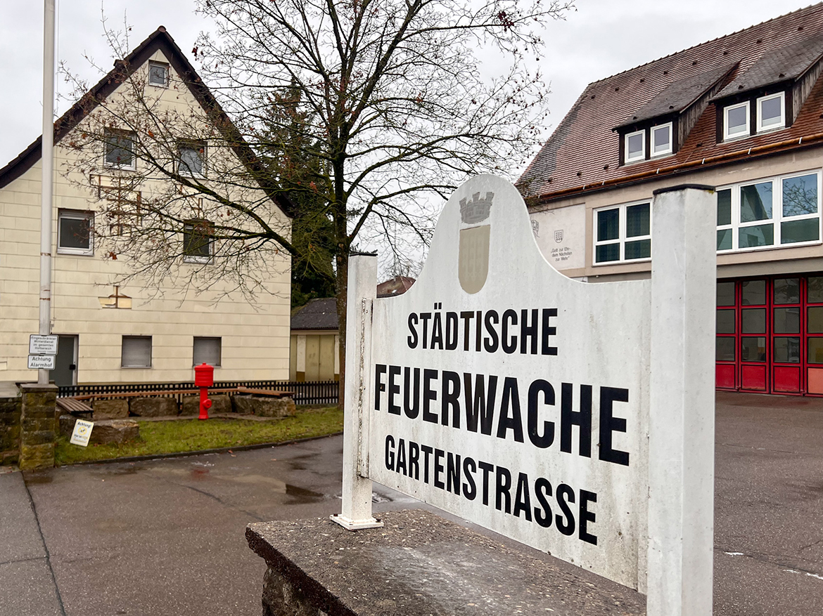Ein Schild mit der Aufschrift "Städtische Feuerwache Gartenstraße", dahinter ein marodes Haus