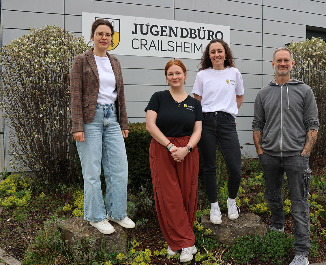 Vier Personen stehen lächelnd vor einem großen Schriftzug "Jugendbüro Crailsheim"