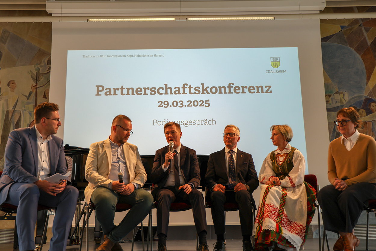 Sechs Menschen sitzen im Halbrund auf einer Bühne