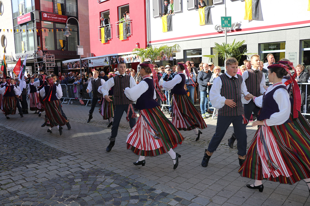 Stadtverwaltung Einige Paare in traditioneller Tracht tanzen auf einem Platz